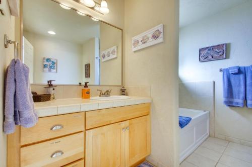 a bathroom with a sink and a mirror and a tub at Quiet Waterfront Escape with Hot Tub and Beach Access! in Gold Beach