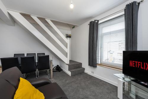 a living room with black chairs and a television at Neath road -Flat 3 in Swansea