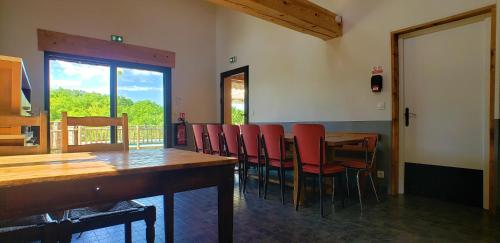 a dining room with a table and red chairs at Gîte de Cayssie in Verrières