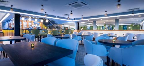 a restaurant with blue chairs and tables and a bar at Foxfields Country Hotel in Langho