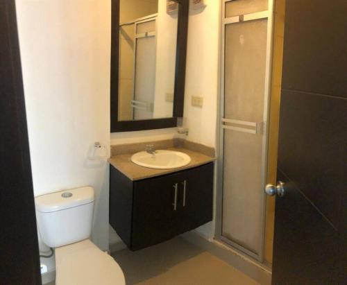 ein Badezimmer mit einem Waschbecken, einem WC und einem Spiegel in der Unterkunft Hermoso departamento frente al mar in Tonsupa
