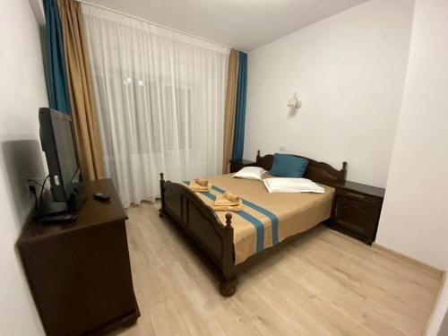 een slaapkamer met een bed, een bureau en een televisie bij Prestige Residence in Alba Iulia