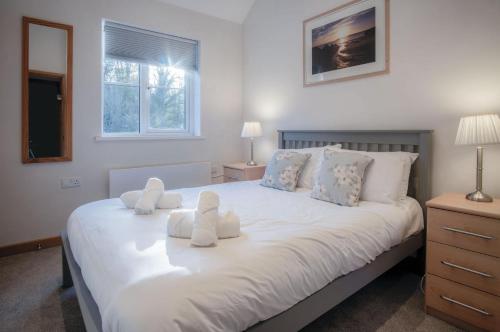 Rhossili Holiday Cottage - 2 Bedroom - Parkmill في Parkmill: غرفة نوم بسرير ابيض كبير مع مخدات بيضاء