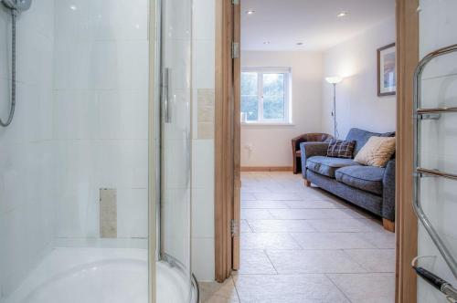Rhossili Holiday Cottage - 2 Bedroom - Parkmill في Parkmill: حمام مع دش زجاجي وأريكة