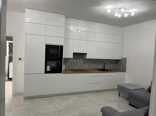 a kitchen with white cabinets and a couch at Apartament Magnoliowy in Owińska
