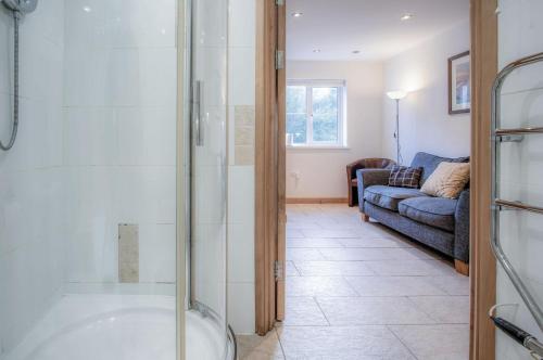 a bathroom with a glass shower and a couch at Three Cliffs Cottage - 2 Bedroom - Parkmill in Parkmill