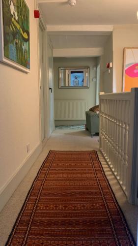 a hallway with a red rug on the floor at The Totnes Guest House. Upstairs at Zappa's in Totnes