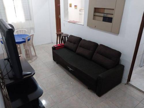 a living room with a black couch and a tv at Casa a 5 minutos a pé da Praia da Enseada! in Bertioga