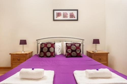 um quarto com uma cama roxa com duas mesas de cabeceira em Privilege Apartment Ciboulette with Rooftop Pool, Village Marina - Olhão em Olhão