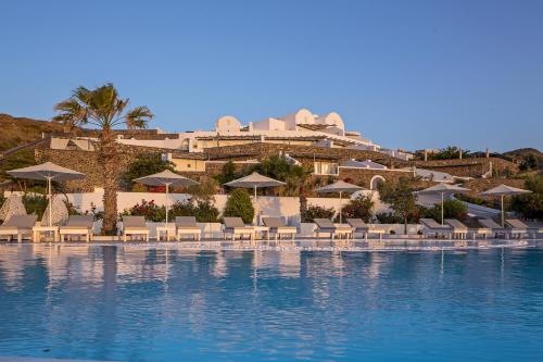 a resort with a pool with chairs and umbrellas at Amber Light Villas in Imerovigli