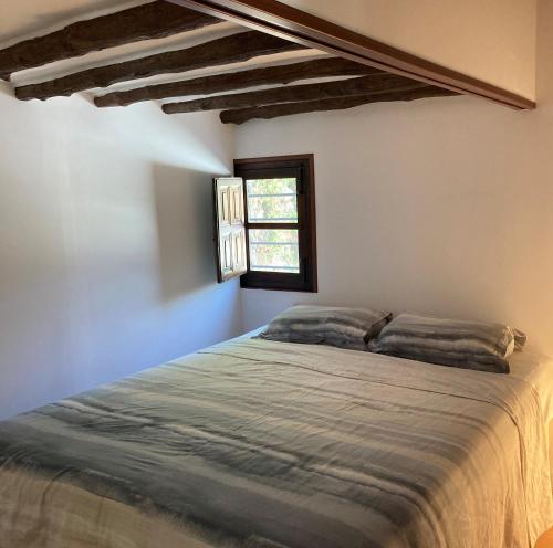 Schlafzimmer mit einem großen Bett und einem Fenster in der Unterkunft Cabaña La Pura Vida Yunquera in Yunquera