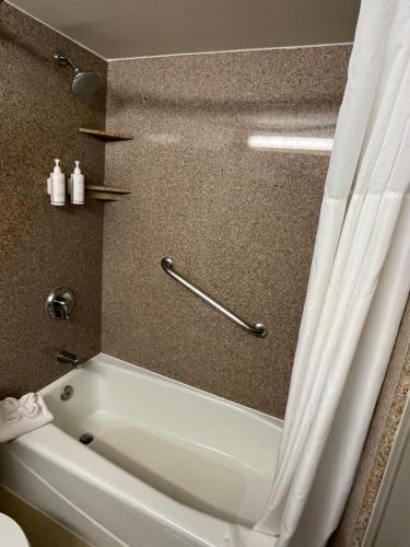 a white bath tub in a bathroom with a shower curtain at Hotel Xola in Moreno Valley