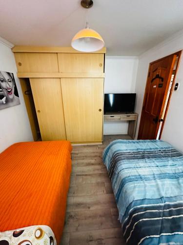 Habitación pequeña con 2 camas y escritorio. en Habitaciones con baño compartido, en Calama
