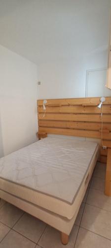 une chambre avec un lit en bois dans une pièce dans l'établissement LES ESTIVALES Proche plage et port 4 pers Grande terrasse clim 2 chambres, à Saint-Cyprien