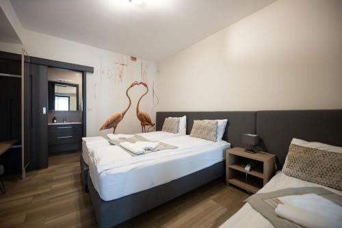 1 dormitorio con 2 camas con esculturas de aves. en Flamingó Panzió és Borház en Etyek