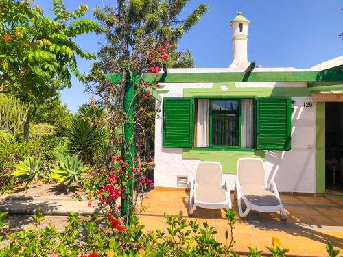 a house with two chairs and a window at Bungalows Cordial Sandy Golf in Maspalomas