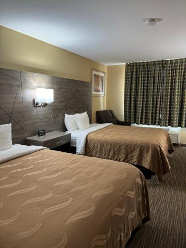 a hotel room with two beds and a chair at Quality Inn near I-72 and Hwy 51 in Forsyth