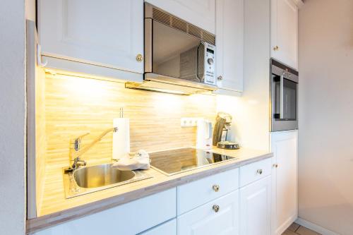 a kitchen with a sink and a microwave at Haus Soenshoern 10 Whg 4 in Munkmarsch