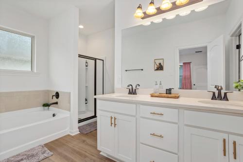 a white bathroom with two sinks and a bath tub at Chic Townhouse by LSU in Baton Rouge