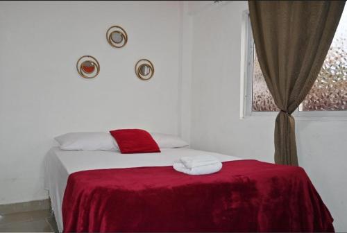 a bedroom with a bed with a red blanket and a window at Hotel Dubaird in Santo Domingo