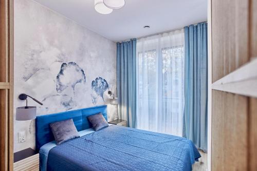 a bedroom with a blue bed and a window at Apartamenty Świnoujście - Seaside Garden in Świnoujście