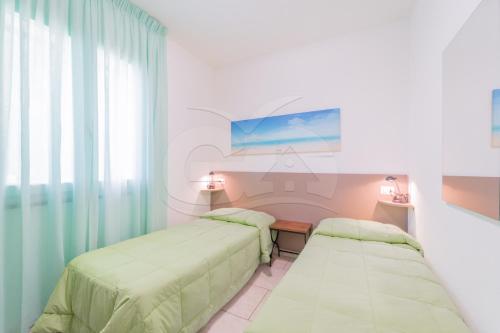 a room with two beds and a table and a window at Albero del Pepe 2 - Goelba in Marina di Campo