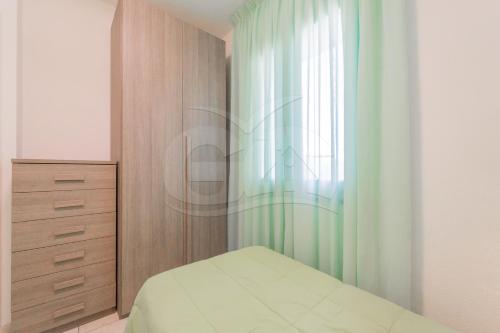 a bedroom with a bed and a dresser and a window at Albero del Pepe 2 - Goelba in Marina di Campo