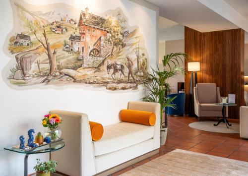 una hall con un divano bianco e un dipinto sul muro di Boutique-HOTEL REMORINO, a Private Selection Hotel a Locarno