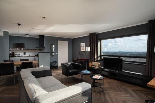 sala de estar con sofá y ventana grande en The Penthouse At The Hague Tower, en La Haya