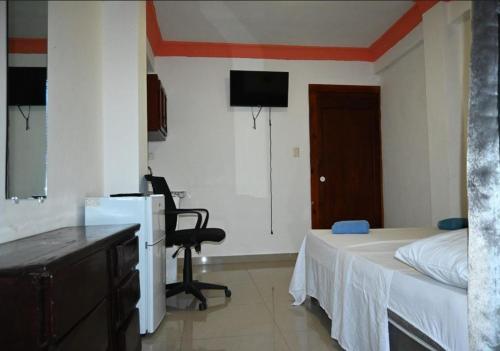 a bedroom with a bed and a desk and a television at Hotel Dubaird in Santo Domingo