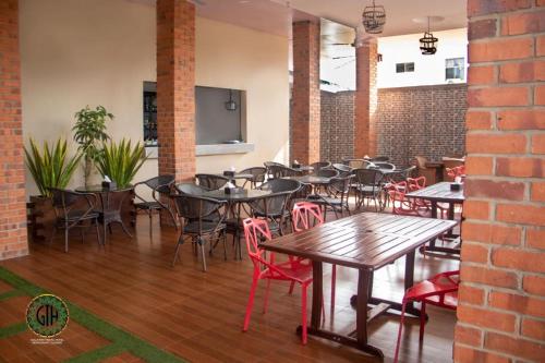 um restaurante com mesas e cadeiras e uma parede de tijolos em Gullivers Travel Hotel em Apenkwa
