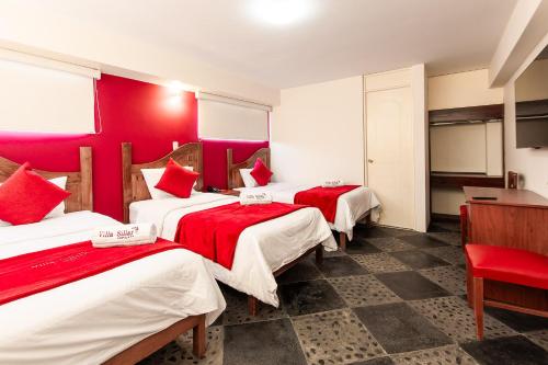 Habitación con 3 camas y paredes de color rojo. en Villa Sillar, en Arequipa