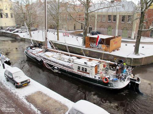 a boat is docked on a river in a city at Spes Mea in Groningen