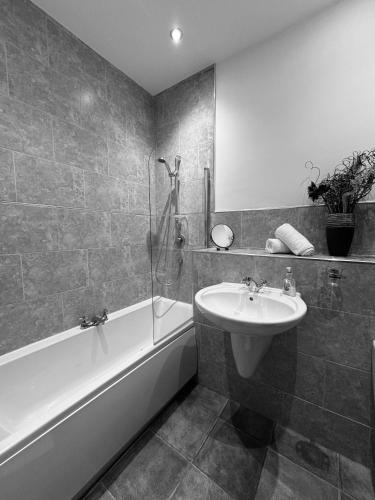 a bathroom with a sink and a bath tub and a sink at Spanish City View 1, Stylish Sea Front Apartment Free Onsite Parking in Whitley Bay