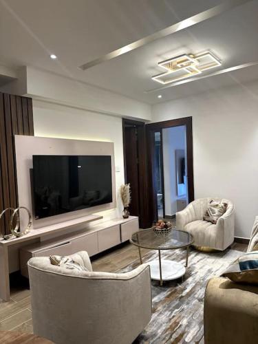 een woonkamer met een flatscreen-tv en stoelen bij Luxurious Apartment in Accra
