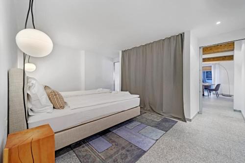 a white bedroom with a bed and a table at Abitaziun Sur Ovel - St Moritz "LOGA ELEGANCE APARTMENT" in St. Moritz