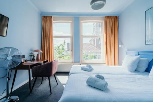 Habitación de hotel con 2 camas, escritorio y ventana en Hotel Omega, en Ámsterdam