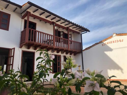 a white building with a balcony and flowers at Rustico Hostel Barichara in Barichara