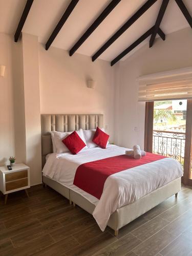 a bedroom with a large bed with red pillows at Hotel Villa Teresita in Sáchica