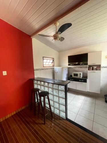 a kitchen with red walls and a counter with stools at Flat Maricá com ar-condicionado in Maricá