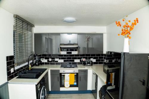 a kitchen with black and white tile on the wall at Dynasty Lodge Manchester - Alison Kelly close in Manchester