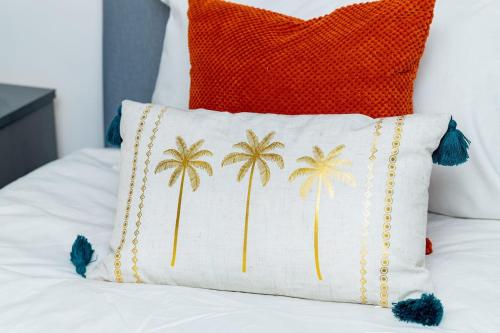 Una almohada naranja y blanca con palmeras sobre una cama. en Dynasty Lodge Manchester - Alison Kelly close, en Mánchester