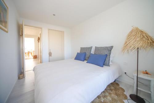 a white bed with blue pillows in a white room at T3 Octopus VUE MER Palavas in Palavas-les-Flots