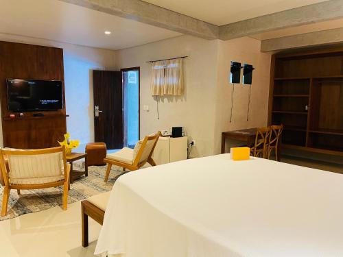 a room with a bed and chairs and a television at Hiu Hotel in Juquei