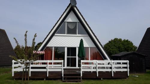 a small house with a triangular roof and white fences at Nurdachhaus PIRATENWEG 131 in Butjadingen