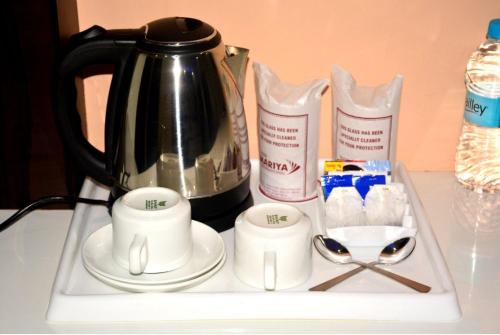 a tray with a tea pot and cups and spoons at HOTEL MARIYA INTERNATIONAL in Bodh Gaya