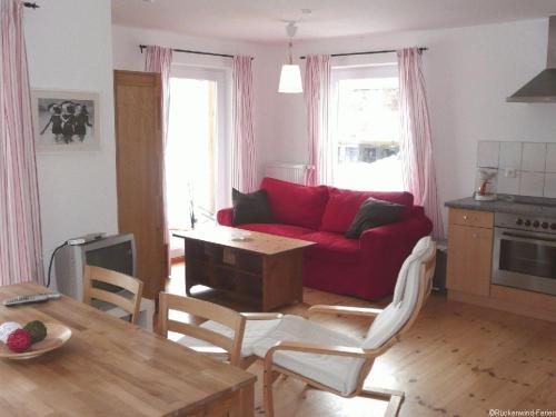 een woonkamer met een rode bank en een tafel bij FLOATING HOUSES Comfort - "Schwimmende Ferienhäuser" - Haus 7 in Kröslin