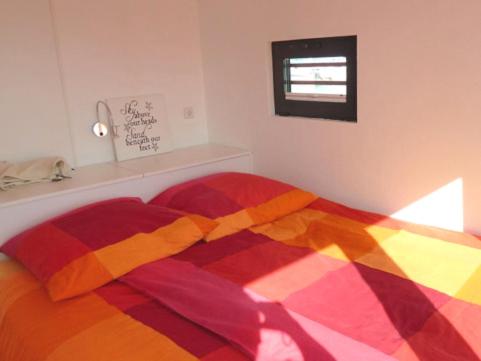 Una cama con un edredón colorido en un dormitorio en Hausboot Floating 44 in Laboe - Boot 3 en Laboe