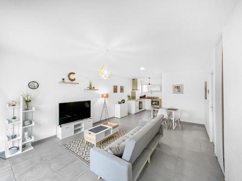 a white living room with a couch and a tv at L'Eclat de la Gironde in La Hourcade