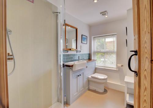 a bathroom with a toilet and a sink and a mirror at Miller's Cottage, The Old Mill in Snape